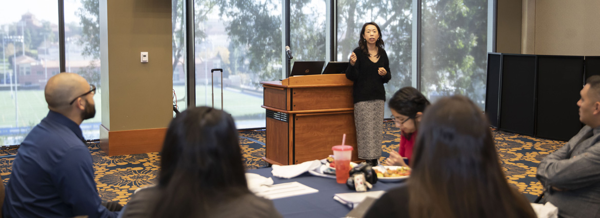 A speaker at a mentorship event addressing a group of members.
